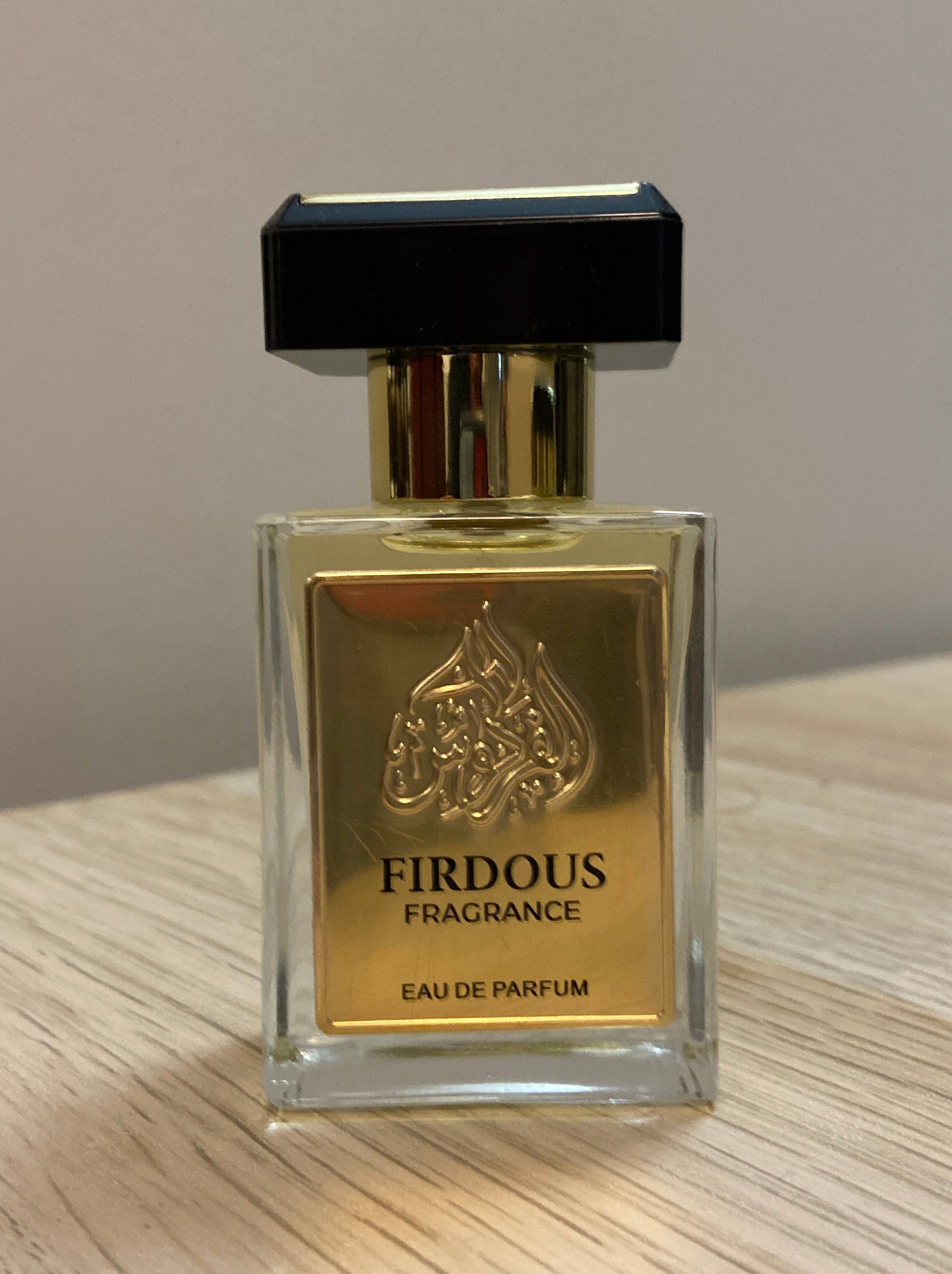 Firdous Fragrance Eau de Parfum bottle on a wooden surface with a neutral background